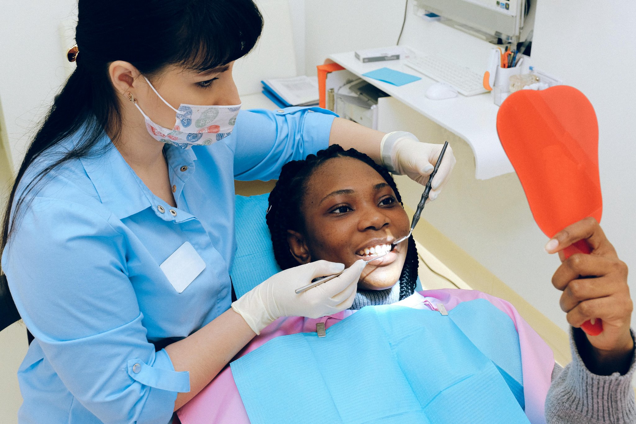 Dentist examining patient smiling in mirror