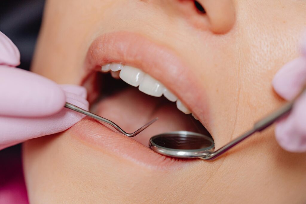 Dentist performing oral examination using dental mirror and probe during a routine check-up